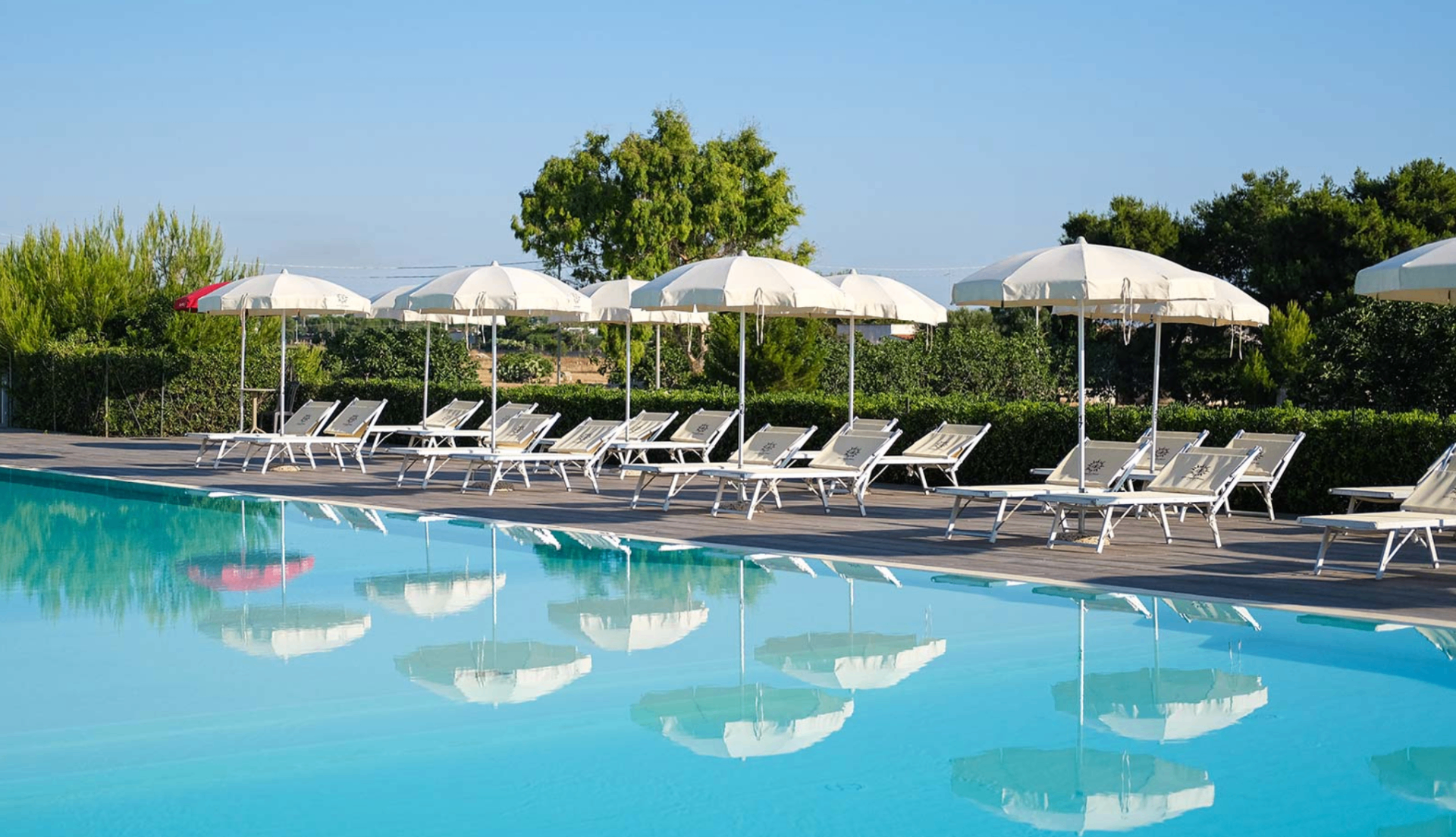 Piscina del Torre Guaceto Greenblu Resort con lettini e ombrelloni